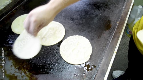 Calentando tortillas de maíz en aceite caliente, tacos dorados, cocina callejera. photo