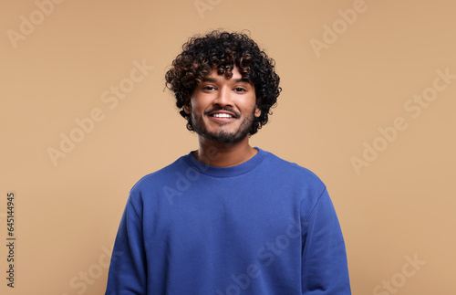 Handsome young smiling man on beige background, space for text