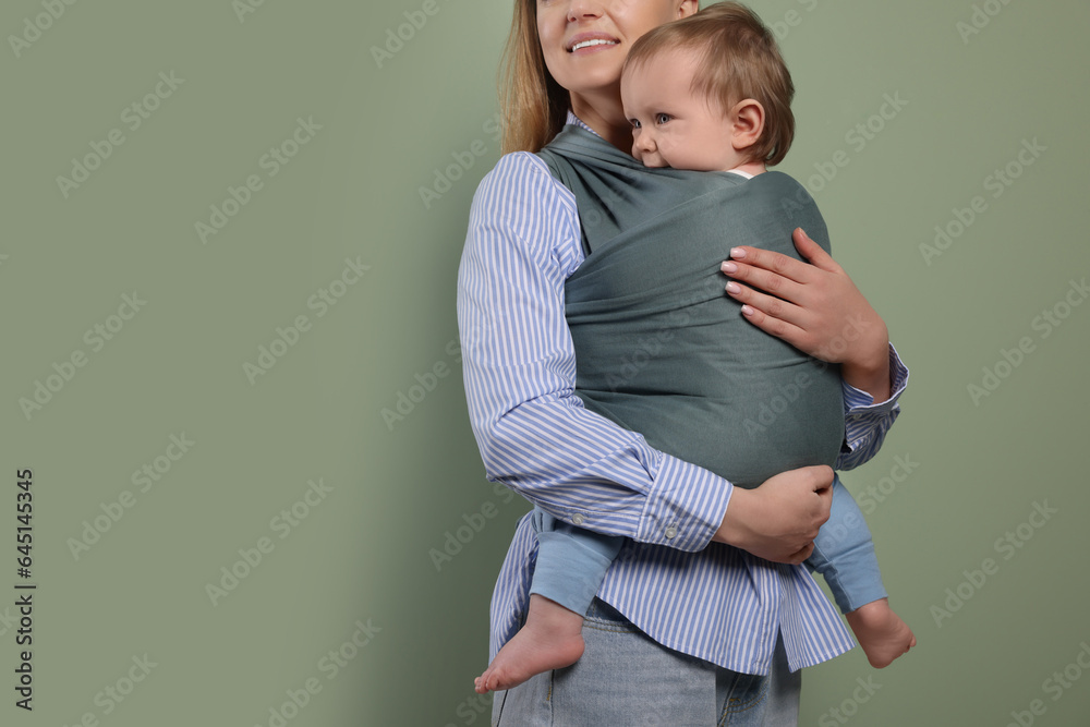 Mother holding her child in baby wrap on olive background, closeup. Space for text