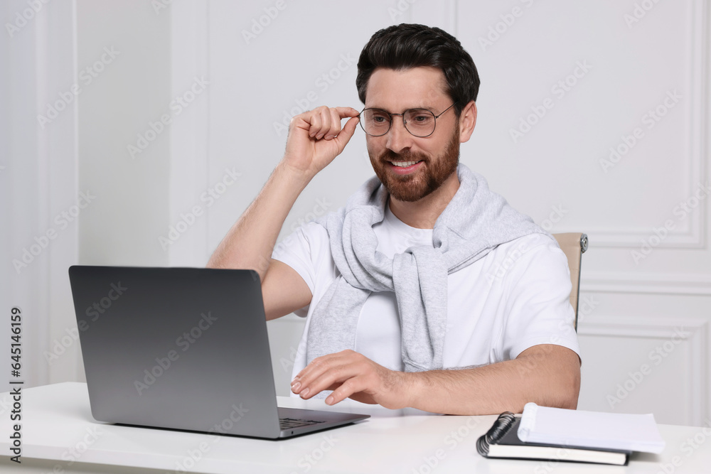 Man using laptop at white table indoors Man using laptop at white table indoors