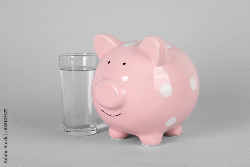 Water scarcity concept. Piggy bank and glass of drink on grey ...