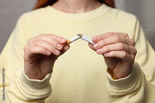 Stop smoking concept. Woman breaking cigarette on light gray background  closeup