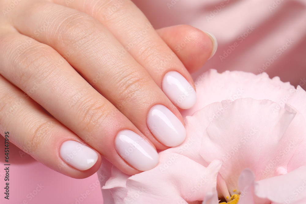 Woman with white nail polish touching eustoma flower, closeup Woman with white nail polish touching eustoma flower, closeup