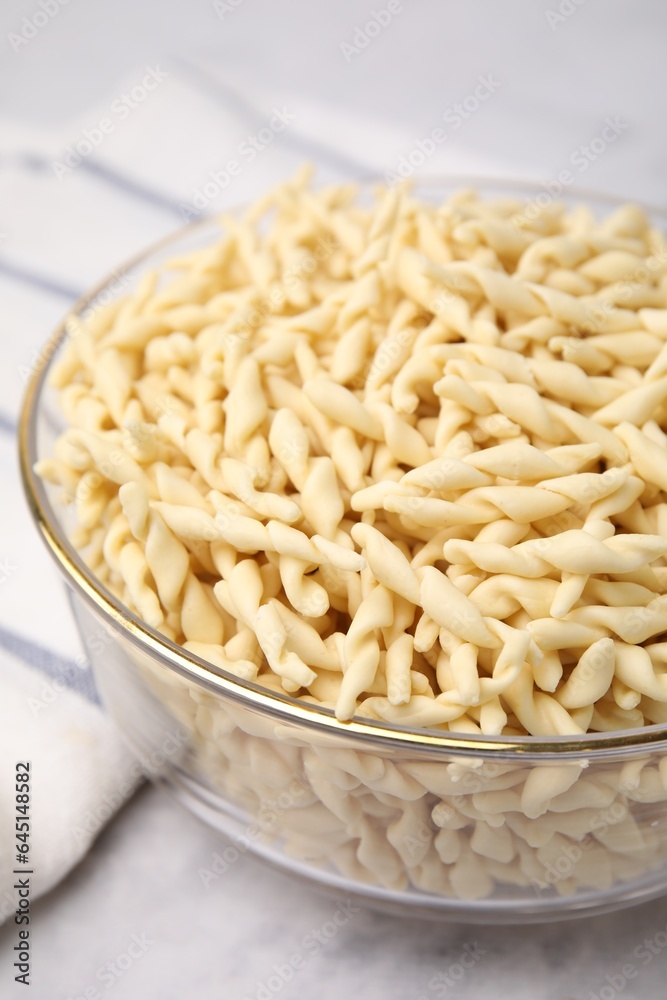 Uncooked trofie pasta in bowl on white table, closeup Uncooked trofie pasta in bowl on white table, closeup
