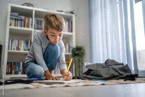 a schoolboy Small caucasian boy play at home draw on the floor