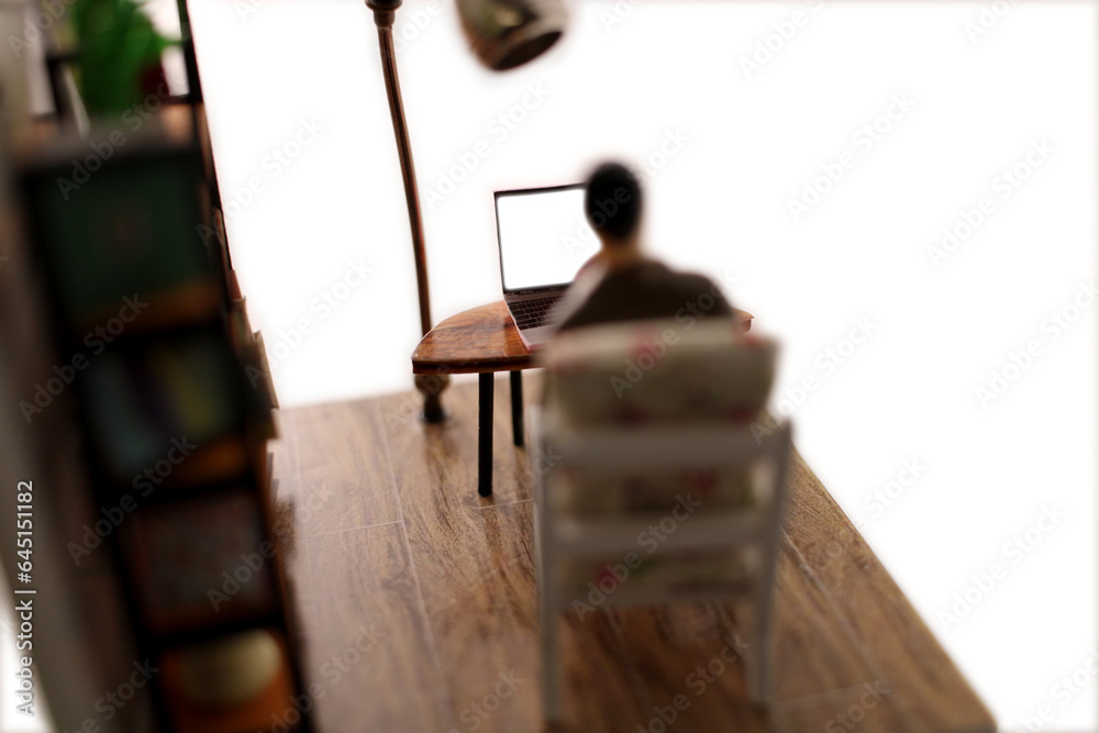 Obraz premium Miniature scene of a man sitting in a chair in a room looking at the blank screen of a laptop computer.