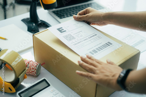 Young business owner putting shipping label on parcel.. photo