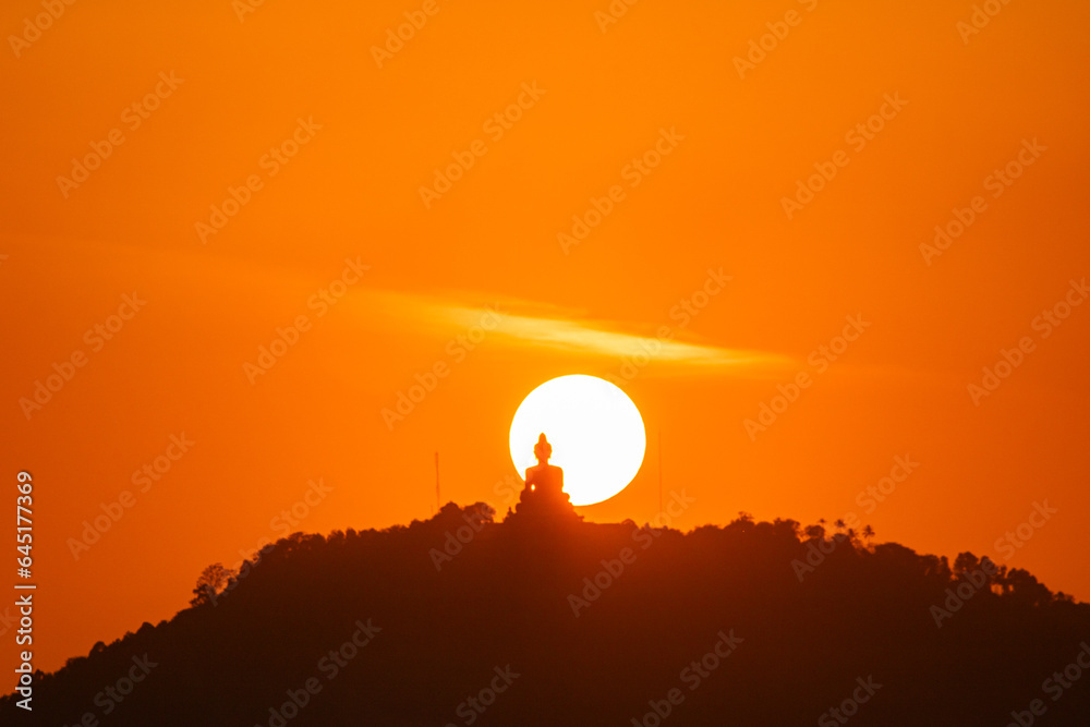.The sun circles in the red sky behind the Big Buddha..Amazing Phuket big Buddha in circle of the sun in red sky..The beauty of the statue fits perfectly with the charming nature. .red sky background .The sun circles in the red sky behind the Big Buddha..Amazing Phuket big Buddha in circle of the sun in red sky..The beauty of the statue fits perfectly with the charming nature. .red sky background