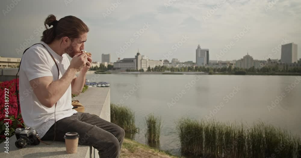 Male tourist eating takeaway food and drinking coffee while admiring cityscape Male tourist eating takeaway food and drinking coffee while admiring cityscape