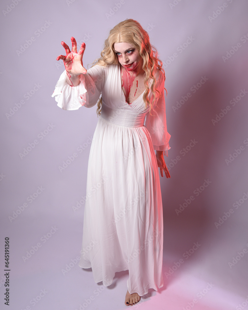 Full length portrait of scary vampire zombie bride, wearing elegant halloween fantasy costume dress with bloody red paint splatter. standing walking pose. Isolated on white studio background Full length portrait of scary vampire zombie bride, wearing elegant halloween fantasy costume dress with bloody red paint splatter. standing walking pose. Isolated on white studio background