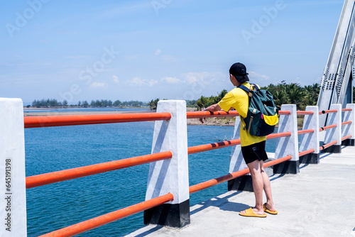 Unidentified young man looking at wide ocean with blue sky