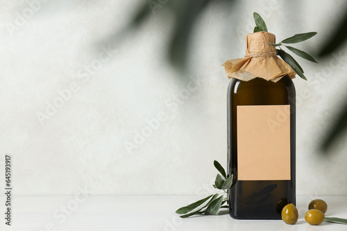 Bottle of olive oil and olives on light background, space for text