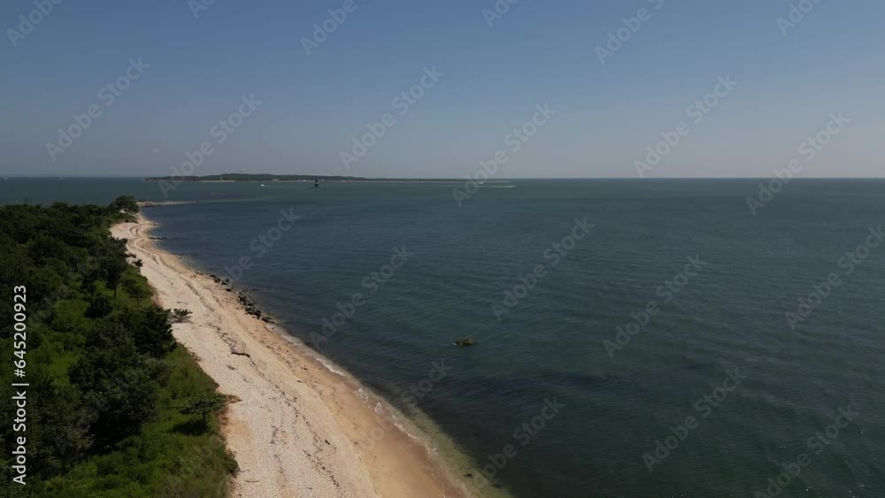 A low angle aerial view from over Orient Point County Park on the east end of Orient Point, NY on a sunny day. The camera dolly in and boom up out over a peaceful and calm Long Island Sound. A low angle aerial view from over Orient Point County Park on the east end of Orient Point, NY on a sunny day. The camera dolly in and boom up out over a peaceful and calm Long Island Sound.