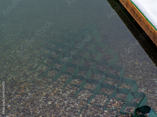 Green polymer geogrid to strengthen the river bank. Strengthening the mountain lake with construction equipment, geogrids that prevent rockfalls and landslides of mobile and loose soils. photo