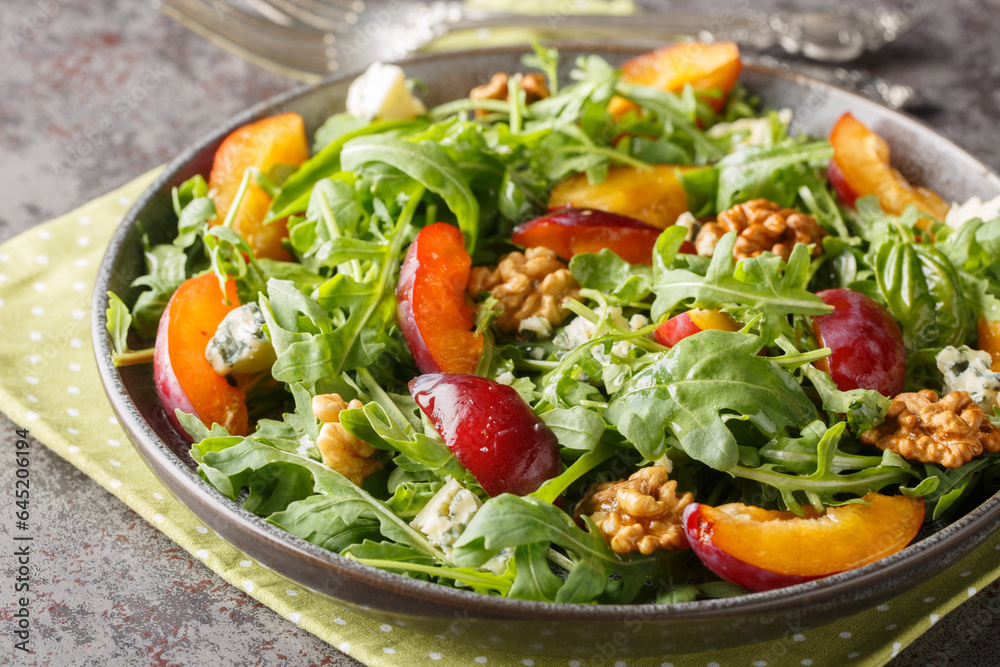 Vitamin breakfast salad of fresh plums, arugula, Gorgonzola cheese and walnuts close-up in a plate on the table. horizontal Vitamin breakfast salad of fresh plums, arugula, Gorgonzola cheese and walnuts close-up in a plate on the table. horizontal