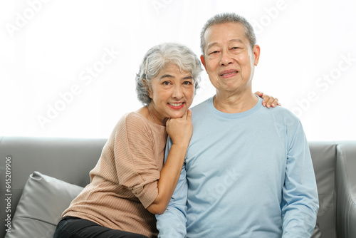 Blissful moments, elderly asian husband and wife sharing joy on sofa, timeless romance, heartwarming moments, peaceful harmony, timeless togetherness, happy family couple, grey hair