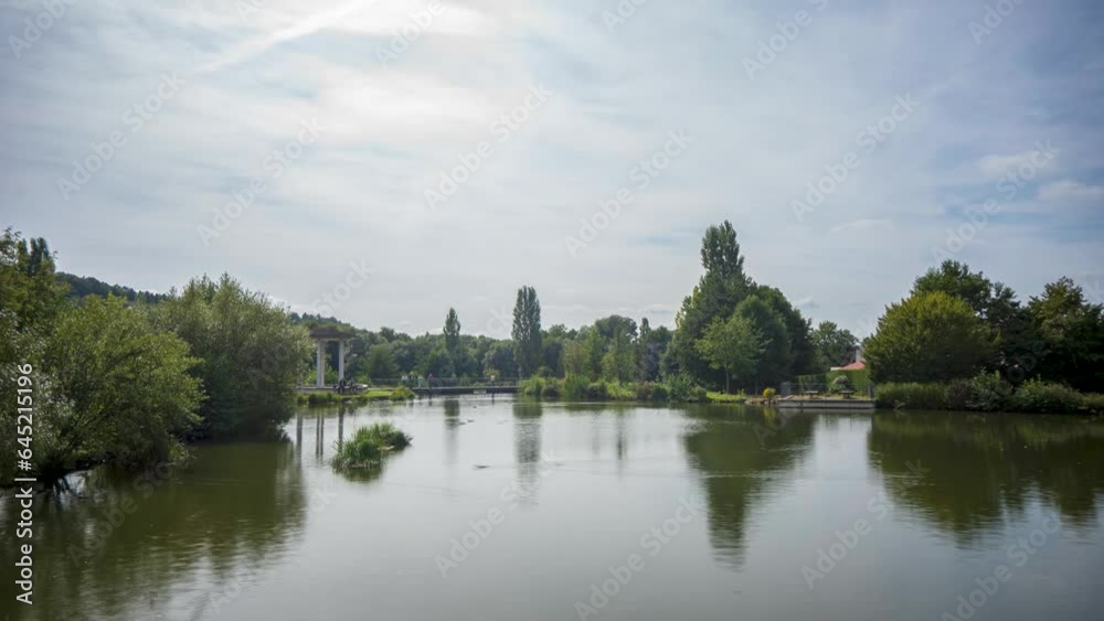Timelapse at a small pond in the spa town Bad Liebenstein in Thuringia with swimming ducks, passing clouds and people in the background Timelapse at a small pond in the spa town Bad Liebenstein in Thuringia with swimming ducks, passing clouds and people in the background