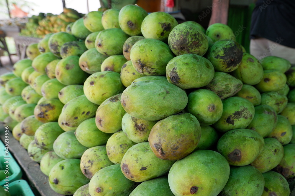 pile of mangoes on a wooden shelf for sale at a traditional market pile of mangoes on a wooden shelf for sale at a traditional market
