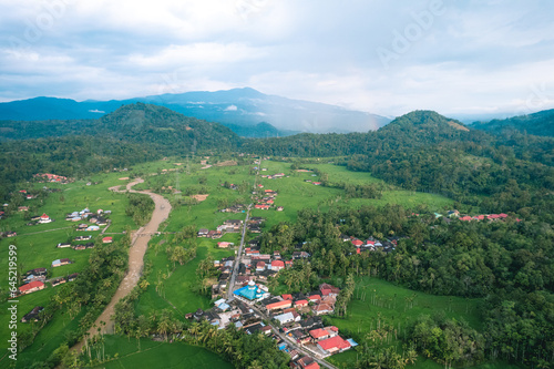 aerial view of sunset in the countryside with a straight road in the background and surrounded by green rice fields photo