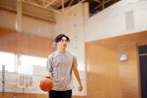 体育館でバスケットボールの練習をする日本人大学生の男性 photo