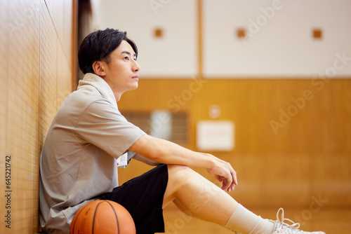 体育館でバスケットボールの練習をする日本人大学生の男性 photo