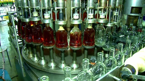 Whiskey and brandy production line. Factory machine pouring alcohol into bottles