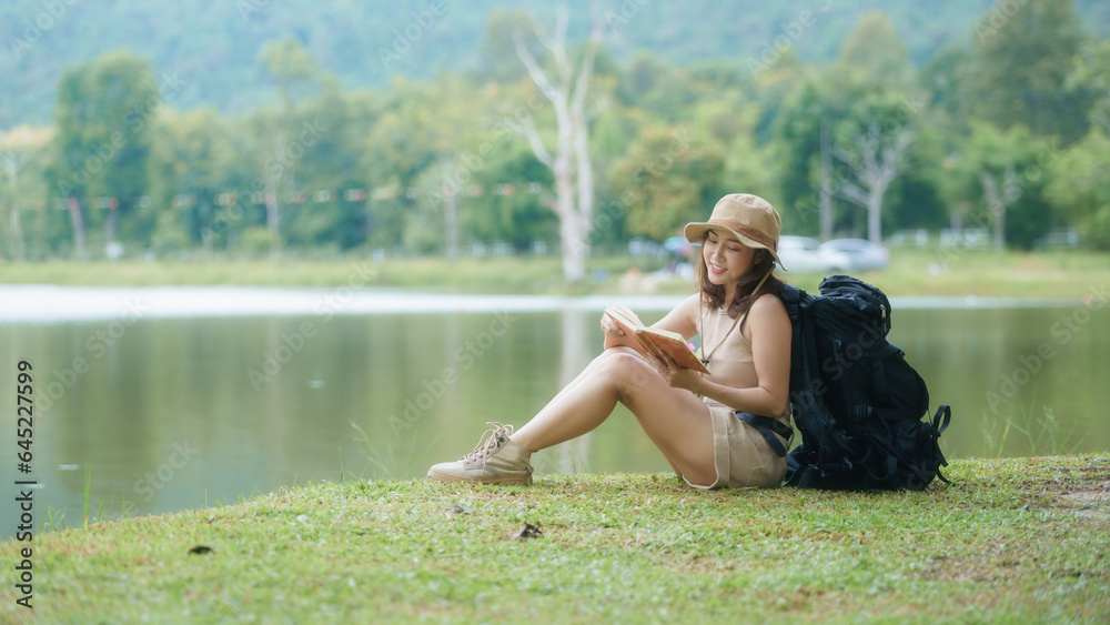 Asian female backpacker reading a book and sitting near the lake. Asian female backpacker reading a book and sitting near the lake.
