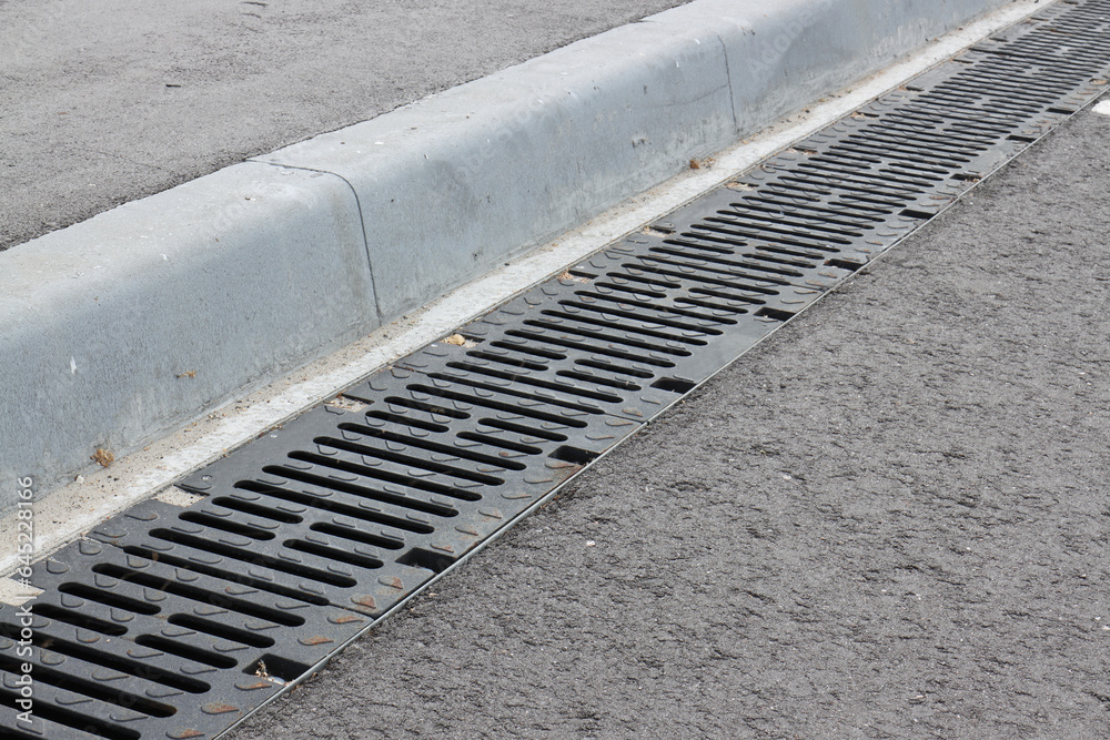 Obraz premium Storm cast-iron grates along the sidewalk curbstone