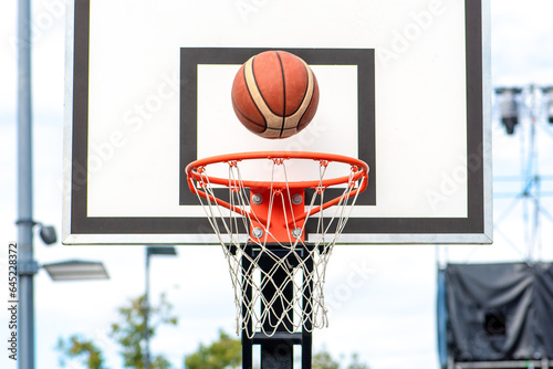 Basketball ball is about to enter the basket. Front view from the player's position playing in the street on outdoor court