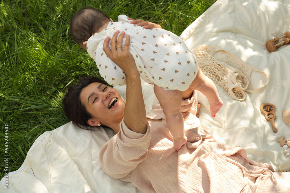 Obraz premium Simple Joys of Life: This photo, capturing a young mother's exuberant play with her baby on a simple grassy lawn, reminds us of the unadulterated happiness found in life's simple moments