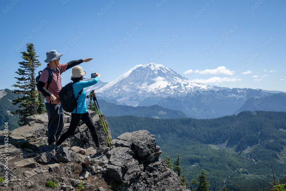 Tourists taking smartphone photos of snow-capped Mount Rainier from Summit Lake Trail. Mt Rainier National Park. Washington State.