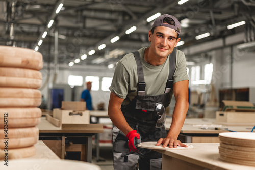 Foto Young carpenter making wood furniture while working in joinery