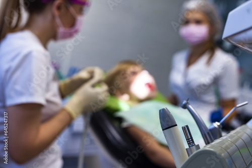 Medical equipment at dental office background, kid patient visit dentist doctor with assistant. Child girl treating teeth in medical clinic. Children healthy dentistry concept. Copy ad text space