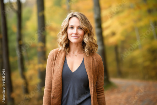 Portrait in the forest of a pleased 30 years old woman. Joyful woman in an outdoor fall scenery having fun at the autumn season. 