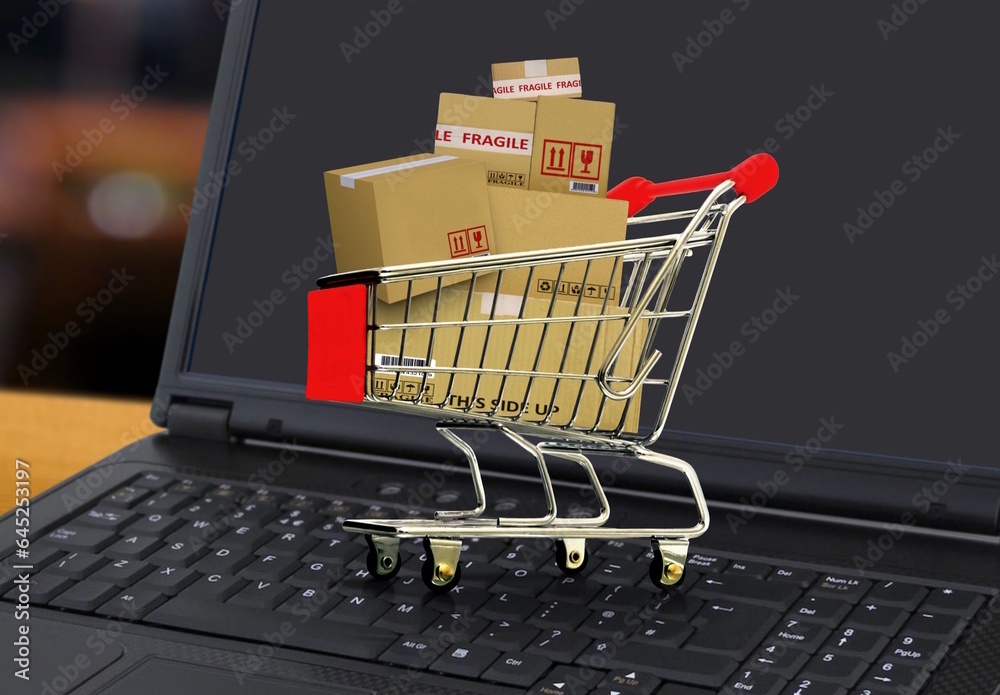 Online shopping and delivery service concept with shopping cart full of boxes on laptop
