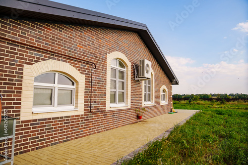 Large one-story brick house with air conditioning on the wall. © andrey