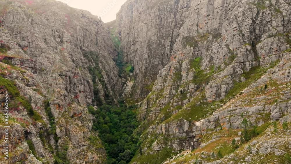 This drone shot captures a picturesque landscape featuring a mountain with intersecting hills. The hills transition from rocky terrain to lush green slopes, creating a blend of natural beauty This drone shot captures a picturesque landscape featuring a mountain with intersecting hills. The hills transition from rocky terrain to lush green slopes, creating a blend of natural beauty
