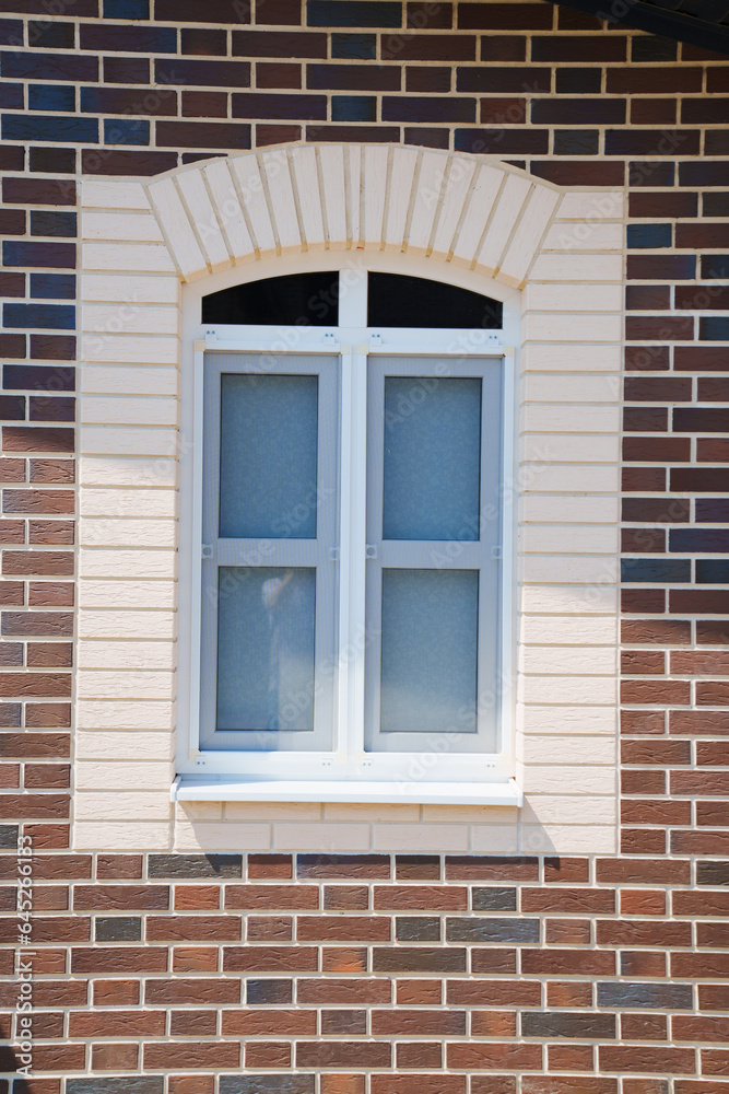 A window on the wall of a new brick house. 