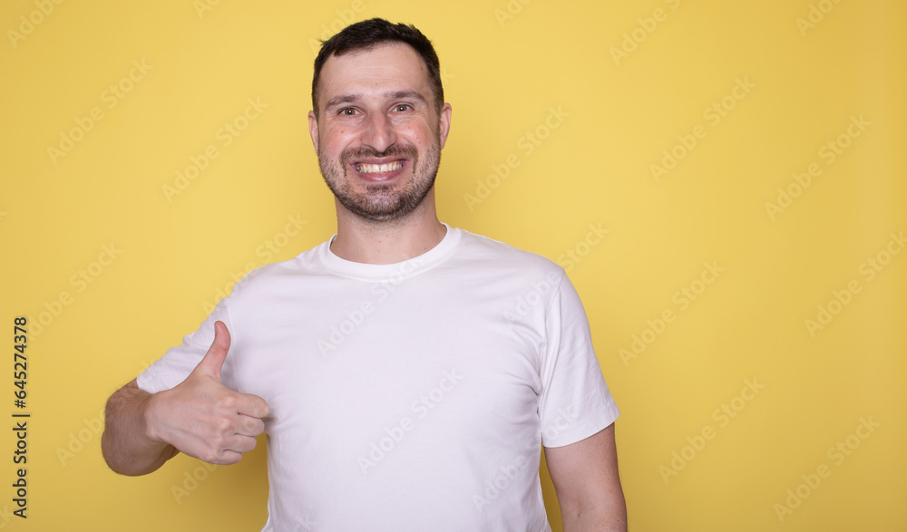 Portrait of cheerful man smiling and showing thumbs up at camera isolated over yellow background. Portrait of cheerful man smiling and showing thumbs up at camera isolated over yellow background.