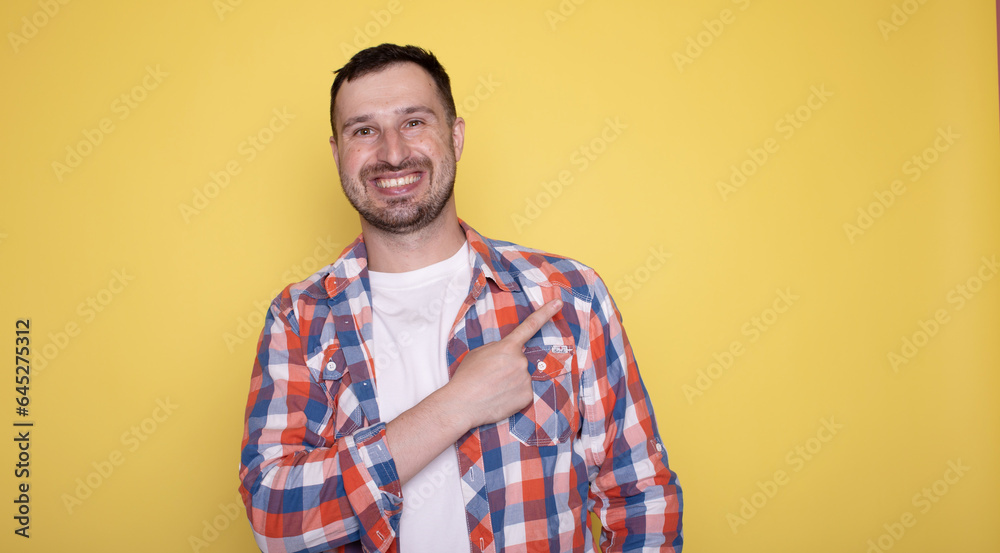 Photo of handsome happy man indicating empty space isolated on yellow background. Photo of handsome happy man indicating empty space isolated on yellow background.