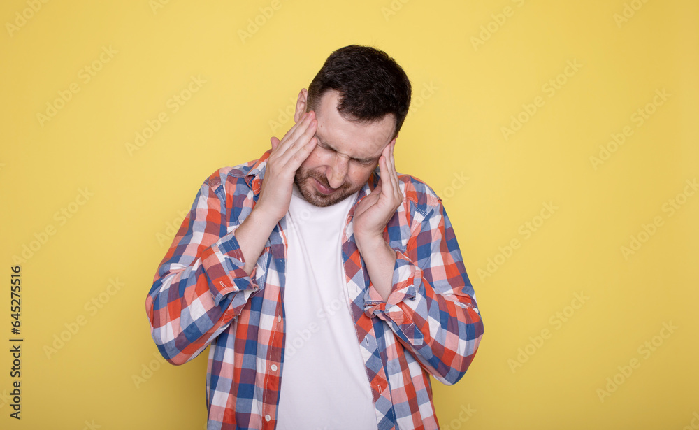 Young caucasian man isolated on yellow background having a head ache, touching front of the face. Young caucasian man isolated on yellow background having a head ache, touching front of the face.