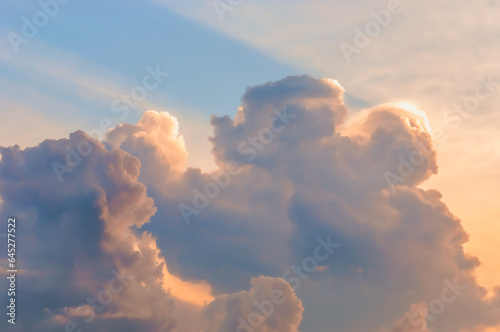 Clouds in the rays of the setting sun on a blue sky. Beautiful natural background in orange-blue tones.