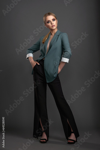 young blonde girl with exquisite beautiful makeup and neat hairstyle in a stylish trouser suit posing in the studio