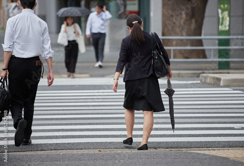 夏の町の交差点で横断歩道を渡る男女サラリーマンの姿