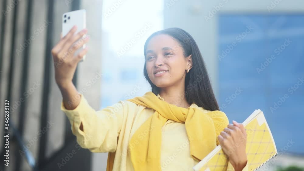 Positive girl student with notebooks talk on smartphone by video call conference with family or friends after lessons at university Pretty young woman blogger create content for social media outdoors Positive girl student with notebooks talk on smartphone by video call conference with family or friends after lessons at university Pretty young woman blogger create content for social media outdoors