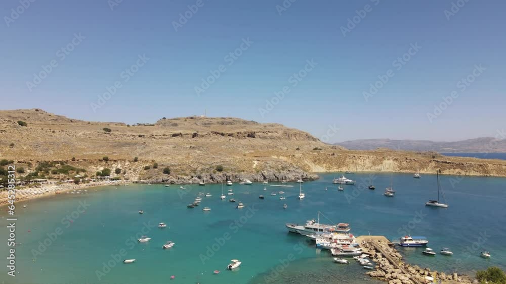Lindos beach, famous bay in Rhodes, Greece with many docked boats, aerial dolly