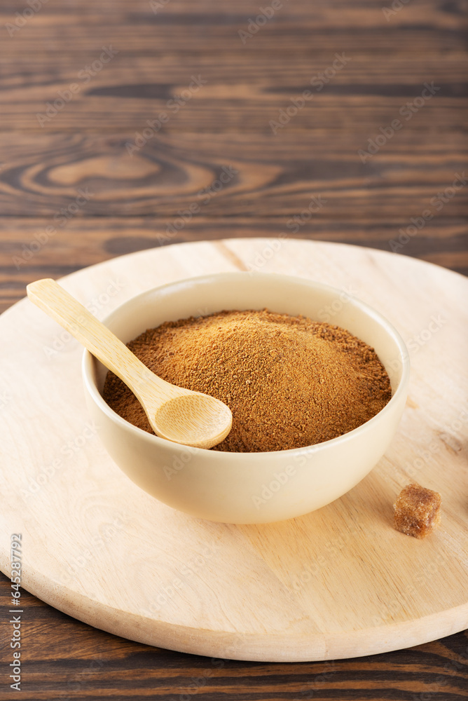 Brown unrefined cane sugar Panela in a bowl on a wooden board. Brown unrefined cane sugar Panela in a bowl on a wooden board.