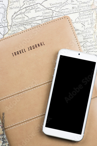 Close-up of a Travel Journal cover featuring a smartphone and a map in the background