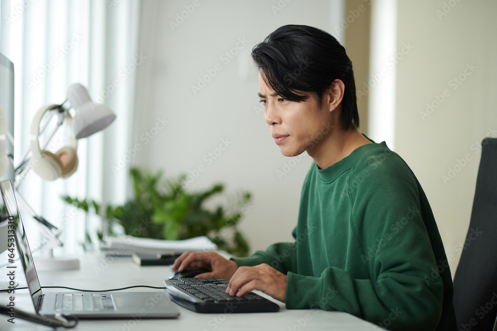 Pensive young software developer looking at laptop screen, checking programming code for mistakes Pensive young software developer looking at laptop screen, checking programming code for mistakes