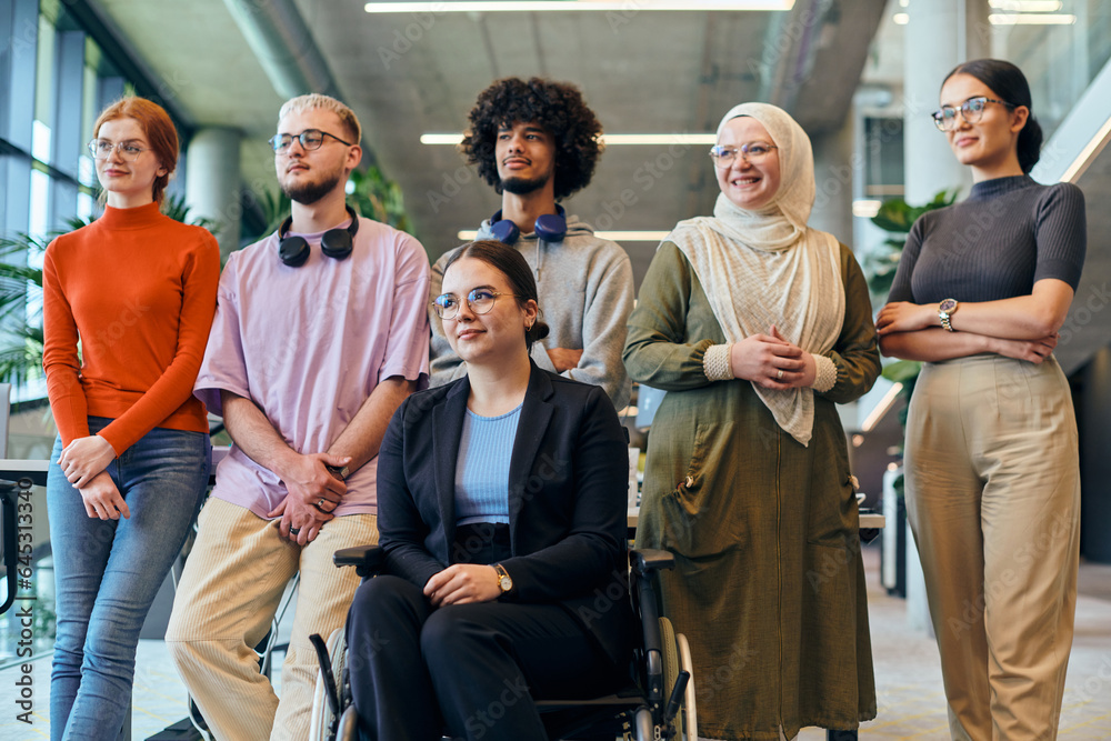 Fototapeta premium In a spacious and modern startup office, a diverse group of business colleagues, including a colleague in a wheelchair, collaborates and interacts, exemplifying inclusivity, diversity, and teamwork in